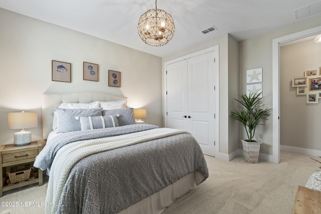 carpeted bedroom with a chandelier, a closet, and baseboards