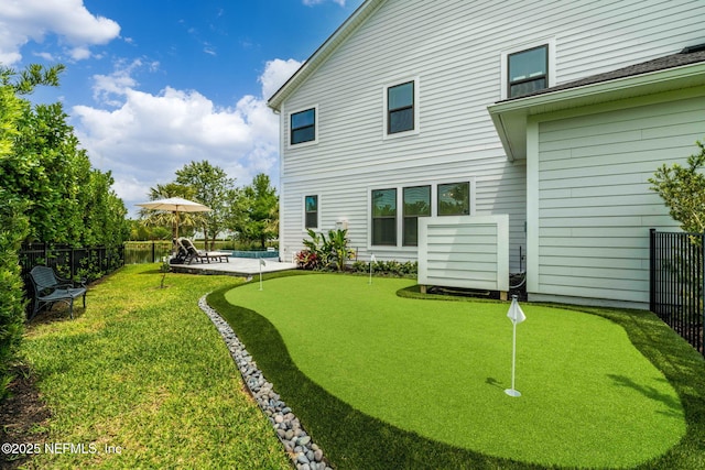 rear view of house with a putting area, fence, a patio, and a swimming pool