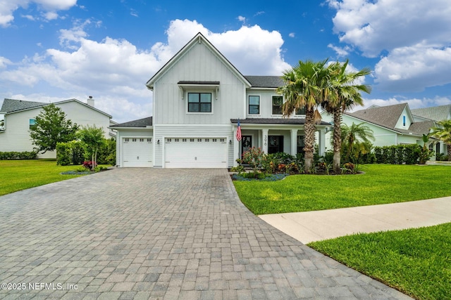 view of front of house featuring board and batten siding, decorative driveway, a front yard, and a garage
