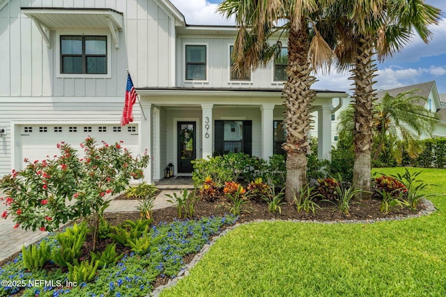 view of front of house with board and batten siding, a front yard, a garage, and a porch