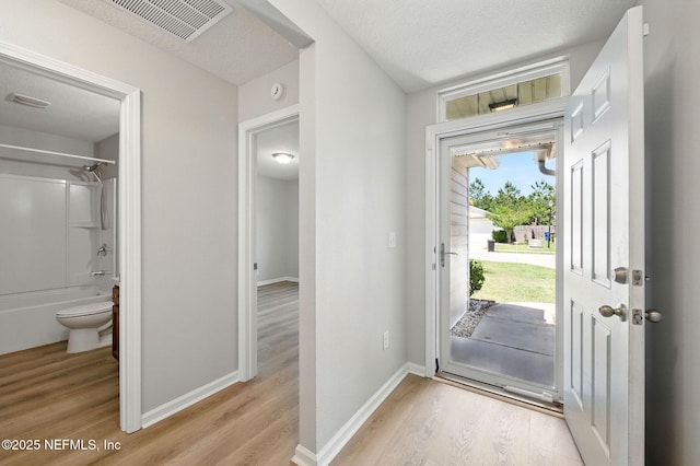 entrance foyer with light wood finished floors, a textured ceiling, and baseboards