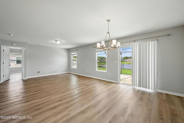 spare room featuring a chandelier, baseboards, wood finished floors, and a textured ceiling