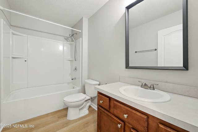 full bathroom with wood finished floors, toilet, a textured ceiling, vanity, and shower / tub combination