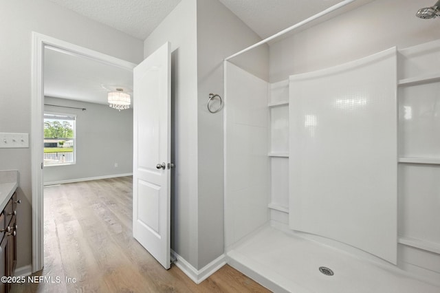 bathroom with wood finished floors, a shower stall, vanity, and a textured ceiling