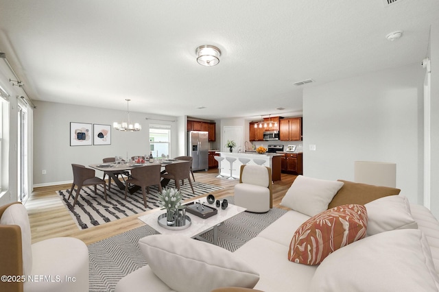 living area with light wood finished floors, a chandelier, and baseboards