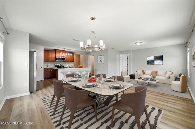 dining space featuring a chandelier, light wood-style flooring, and baseboards