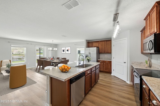 kitchen with stainless steel appliances, a sink, light wood-style floors, light countertops, and a textured ceiling