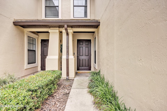 view of exterior entry with stucco siding and covered porch