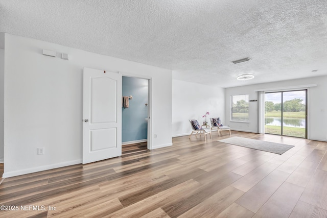 spare room with wood finished floors, a textured ceiling, and baseboards