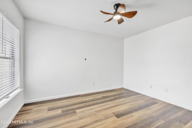 spare room featuring ceiling fan, wood finished floors, a textured ceiling, and baseboards
