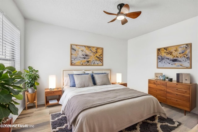 bedroom with light wood-style flooring, a textured ceiling, and ceiling fan
