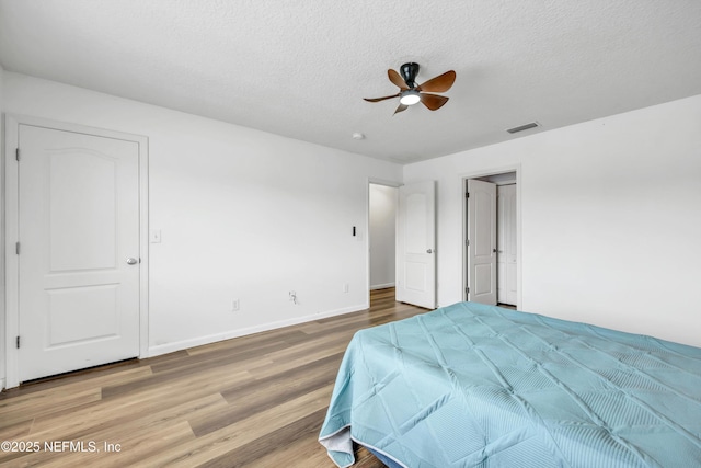 bedroom featuring wood finished floors, baseboards, a textured ceiling, and a ceiling fan