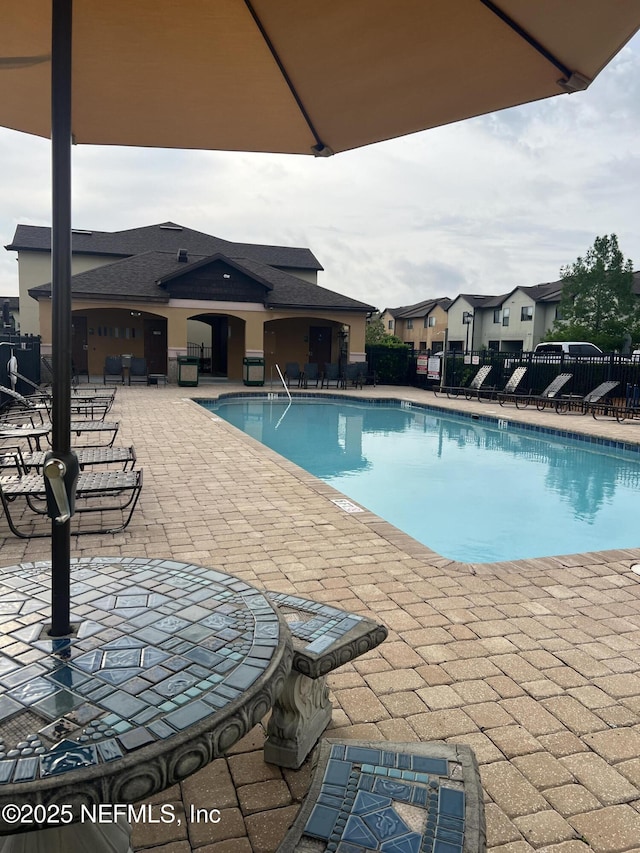 community pool with fence and a patio area