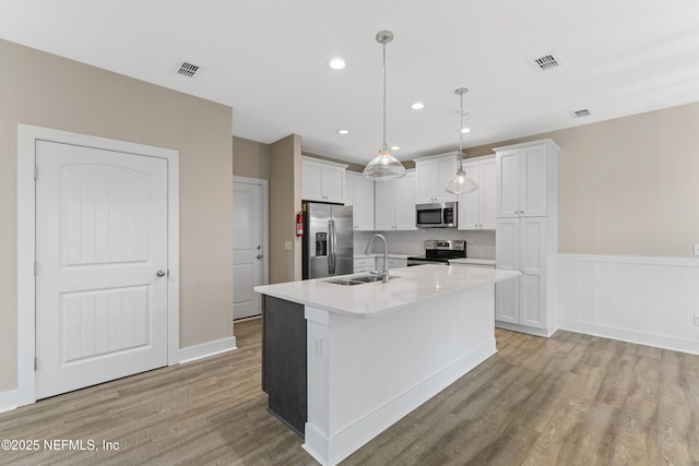 1339 Date St, Fernandina Beach, FL 32034 - kitchen with stainless steel appliances, a sink, light wood finished floors, light countertops, and white cabinets