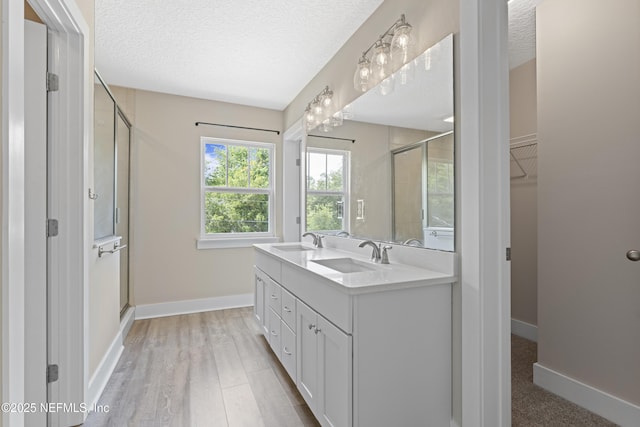 1339 Date St, Fernandina Beach, FL 32034 - full bath featuring a stall shower, a textured ceiling, double vanity, baseboards, and wood finished floors