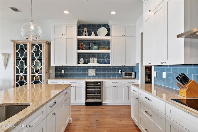 2540 Beach Blvd, Jacksonville Beach, FL 32250 - kitchen with wine cooler, wall chimney range hood, white cabinets, decorative light fixtures, and light wood-type flooring