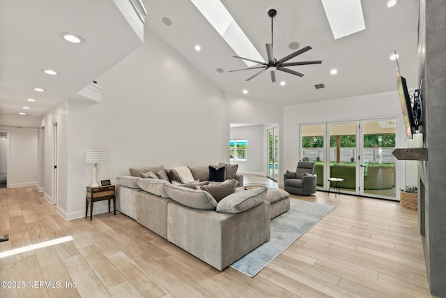 living area with a skylight, high vaulted ceiling, light wood-type flooring, recessed lighting, and a ceiling fan