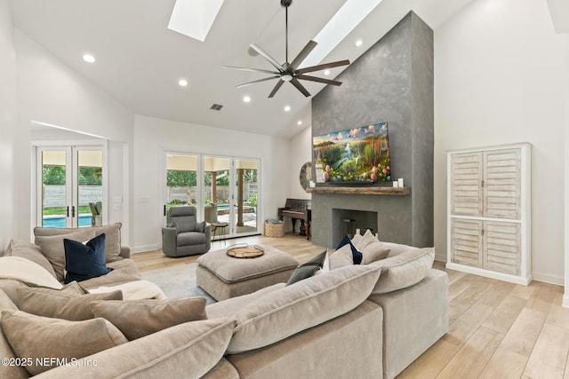 living area with high vaulted ceiling, recessed lighting, a skylight, light wood-type flooring, and baseboards