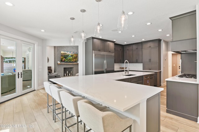 kitchen featuring a sink, built in refrigerator, gas stovetop, recessed lighting, and light wood-style flooring