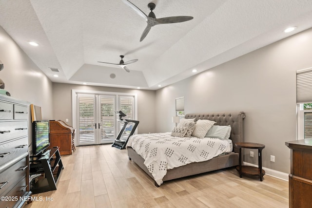 bedroom featuring a tray ceiling, access to exterior, light wood finished floors, baseboards, and a textured ceiling