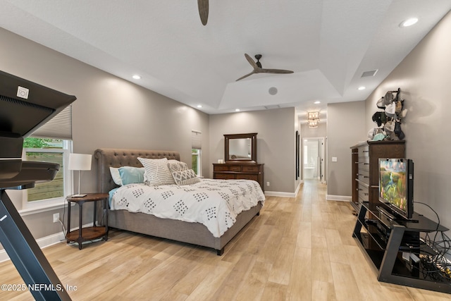 bedroom with light wood-type flooring, a raised ceiling, baseboards, recessed lighting, and ceiling fan