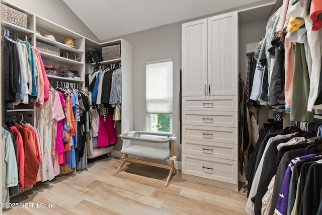 spacious closet with light wood finished floors and vaulted ceiling