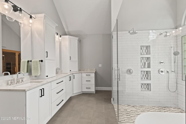 full bathroom featuring a tile shower, tile patterned flooring, lofted ceiling, double vanity, and baseboards