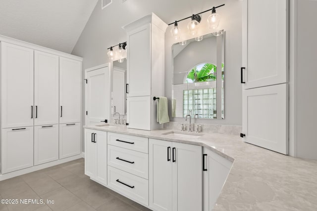 bathroom with vaulted ceiling, tile patterned flooring, and double vanity