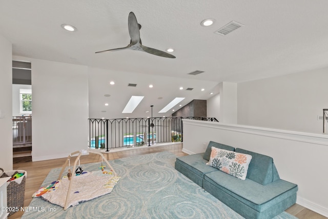 living room featuring wood finished floors, a skylight, recessed lighting, ceiling fan, and baseboards