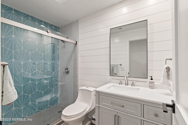full bathroom featuring a shower stall, vanity, toilet, and a textured ceiling