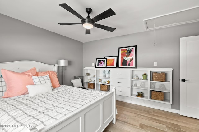 bedroom featuring attic access, light wood-type flooring, and ceiling fan