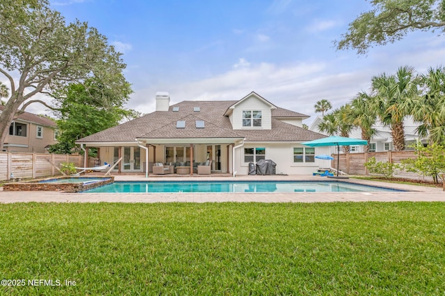 back of property with an outdoor living space, a chimney, roof with shingles, a patio, and a pool with connected hot tub
