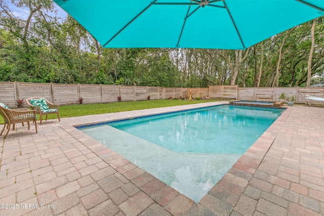 view of swimming pool with a patio area, a fenced backyard, and view of wooded area