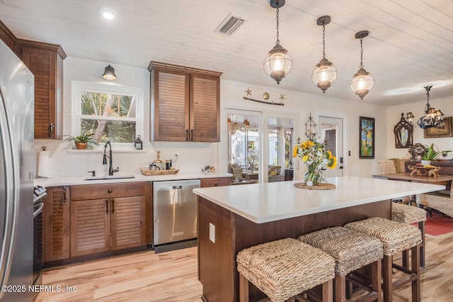 120 Swallow Rd, Saint Augustine, FL 32086 - kitchen with appliances with stainless steel finishes, a sink, light countertops, a kitchen bar, and light wood-style floors