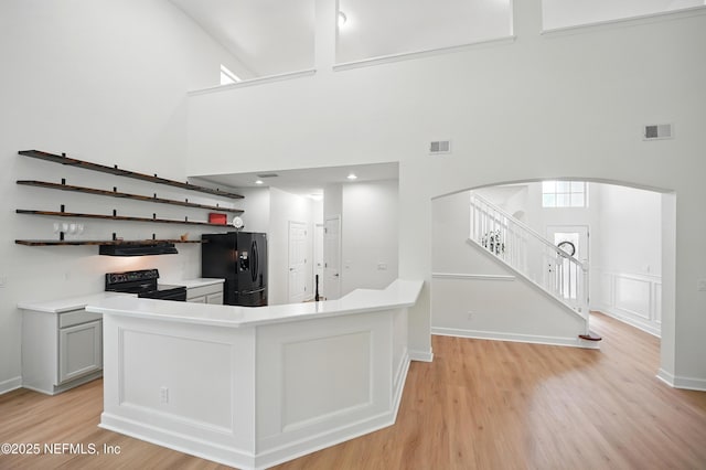 2012 Belle Grove Ter, Fleming Island, FL 32003 - kitchen featuring black appliances, a high ceiling, arched walkways, light wood-type flooring, and light countertops