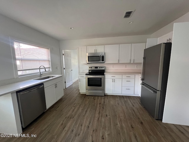 kitchen featuring stainless steel appliances, a sink, white cabinets, and recessed lighting