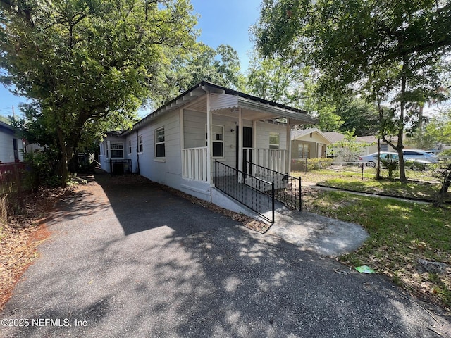 shotgun-style home featuring fence, a porch, driveway, and central air condition unit