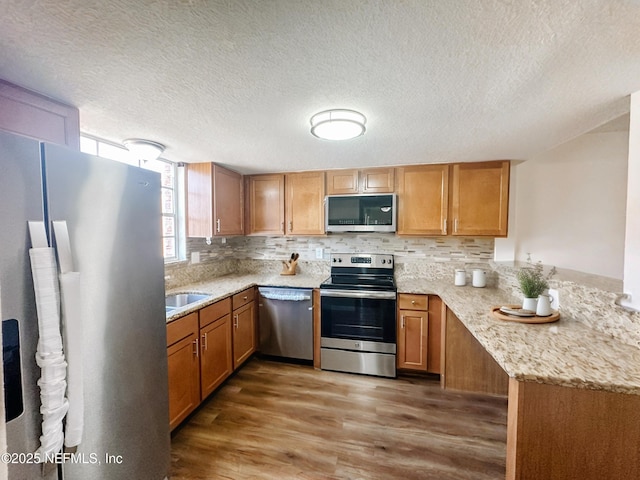 5201 Atlantic Blvd Unit 299, Jacksonville, FL 32207 - kitchen with appliances with stainless steel finishes, wood finished floors, decorative backsplash, light stone counters, and a textured ceiling