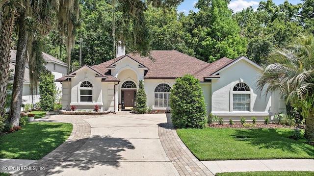 view of front of home with stucco siding, driveway, and a front yard