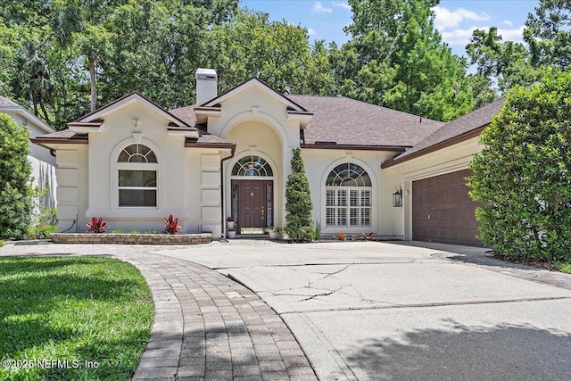 mediterranean / spanish home with a chimney, concrete driveway, stucco siding, a garage, and a shingled roof