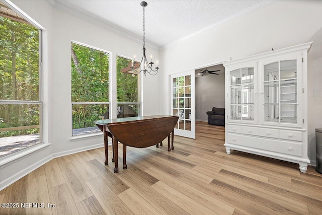 dining area with light wood-type flooring, ornamental molding, a chandelier, a textured ceiling, and baseboards