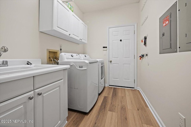laundry area featuring cabinet space, independent washer and dryer, light wood-style floors, and electric panel