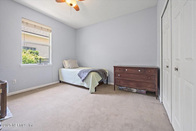 carpeted bedroom featuring a closet, baseboards, a ceiling fan, and a textured ceiling