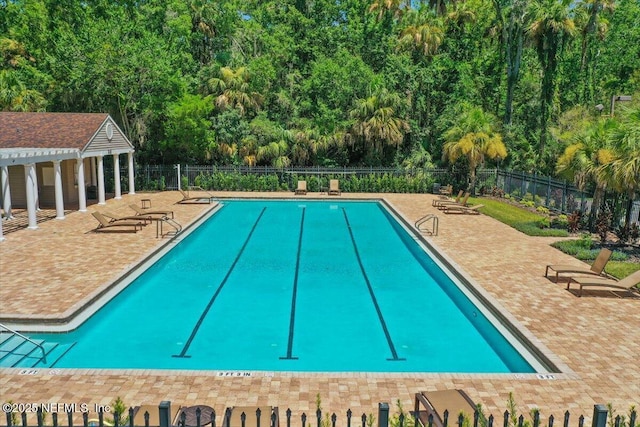 community pool with fence, a patio, and view of scattered trees