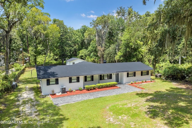5092 Harvey Grant Rd, Fleming Island, FL 32003 - view of front of property with central air condition unit, a shingled roof, and a forest view