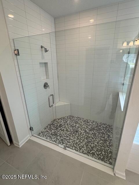 full bath featuring tile patterned floors, a stall shower, and baseboards