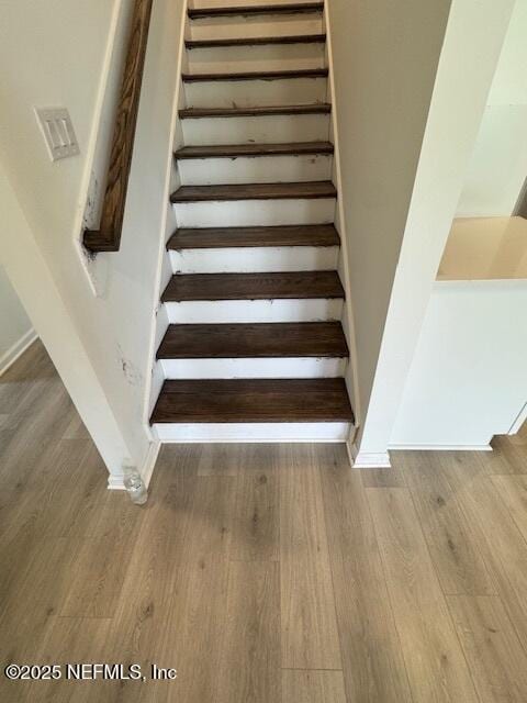stairway with wood finished floors and baseboards