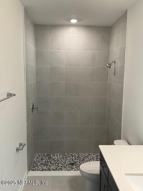 full bathroom with a tile shower, vanity, toilet, and recessed lighting