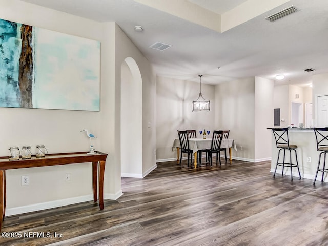 dining space with wood finished floors, arched walkways, and baseboards
