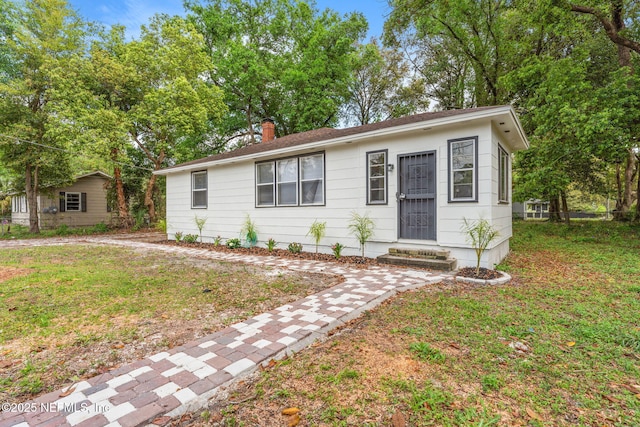 view of front of home with a front yard and a chimney